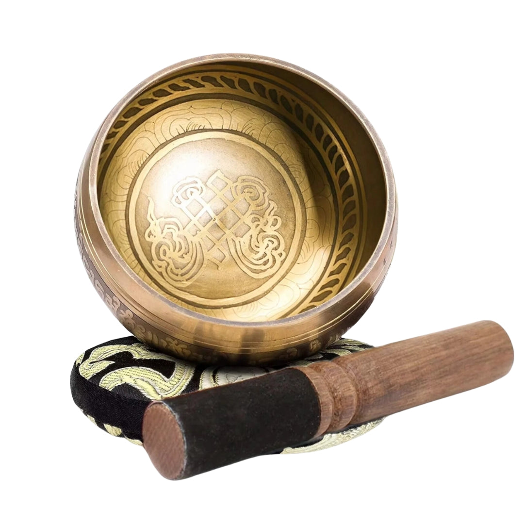 Image of a handcrafted CalmEcho Bowl Tibetan singing bowl, made in Nepal. The bowl is golden with an engraved traditional internal design, accompanied by a wooden striker with a padded end and a decorative blue and gold cushion. The set is used for meditation, yoga, and mindfulness practices, emitting relaxing and resonant sounds.