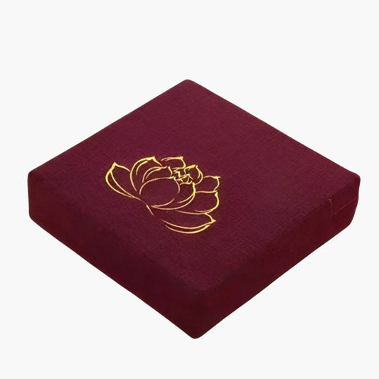 The CalmCore Meditation Cushion is a premium support cushion designed for yoga, meditation, and relaxation. Made from a blend of eco-friendly linen and cotton, it offers durability, breathability, and a soft yet firm structure for optimal comfort. The cushion features a deep burgundy color with an elegant gold lotus embroidery on the top, symbolizing peace and spiritual growth.