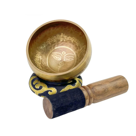 Image of a handcrafted CalmEcho Bowl Tibetan singing bowl, made in Nepal. The bowl is golden with an engraved traditional internal design, accompanied by a wooden striker with a padded end and a decorative blue and gold cushion. The set is used for meditation, yoga, and mindfulness practices, emitting relaxing and resonant sounds.