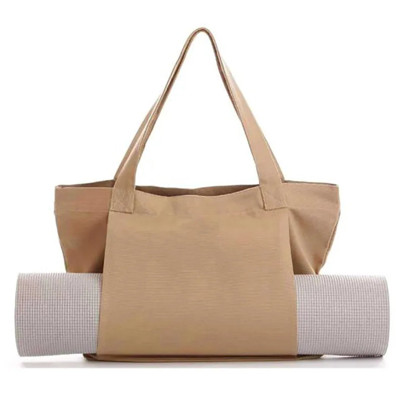 Image of the Essence Yoga Tote, a apricot, washable canvas bag designed for carrying yoga mats and workout essentials. The tote features a sleek and spacious design with adjustable straps for easy carrying. Shown with a rolled yoga mat secured in its front pocket, the tote is lightweight, foldable, and perfect for yogis on the go.