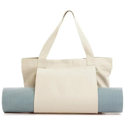 Image of the Essence Yoga Tote, a white, washable canvas bag designed for carrying yoga mats and workout essentials. The tote features a sleek and spacious design with adjustable straps for easy carrying. Shown with a rolled yoga mat secured in its front pocket, the tote is lightweight, foldable, and perfect for yogis on the go.