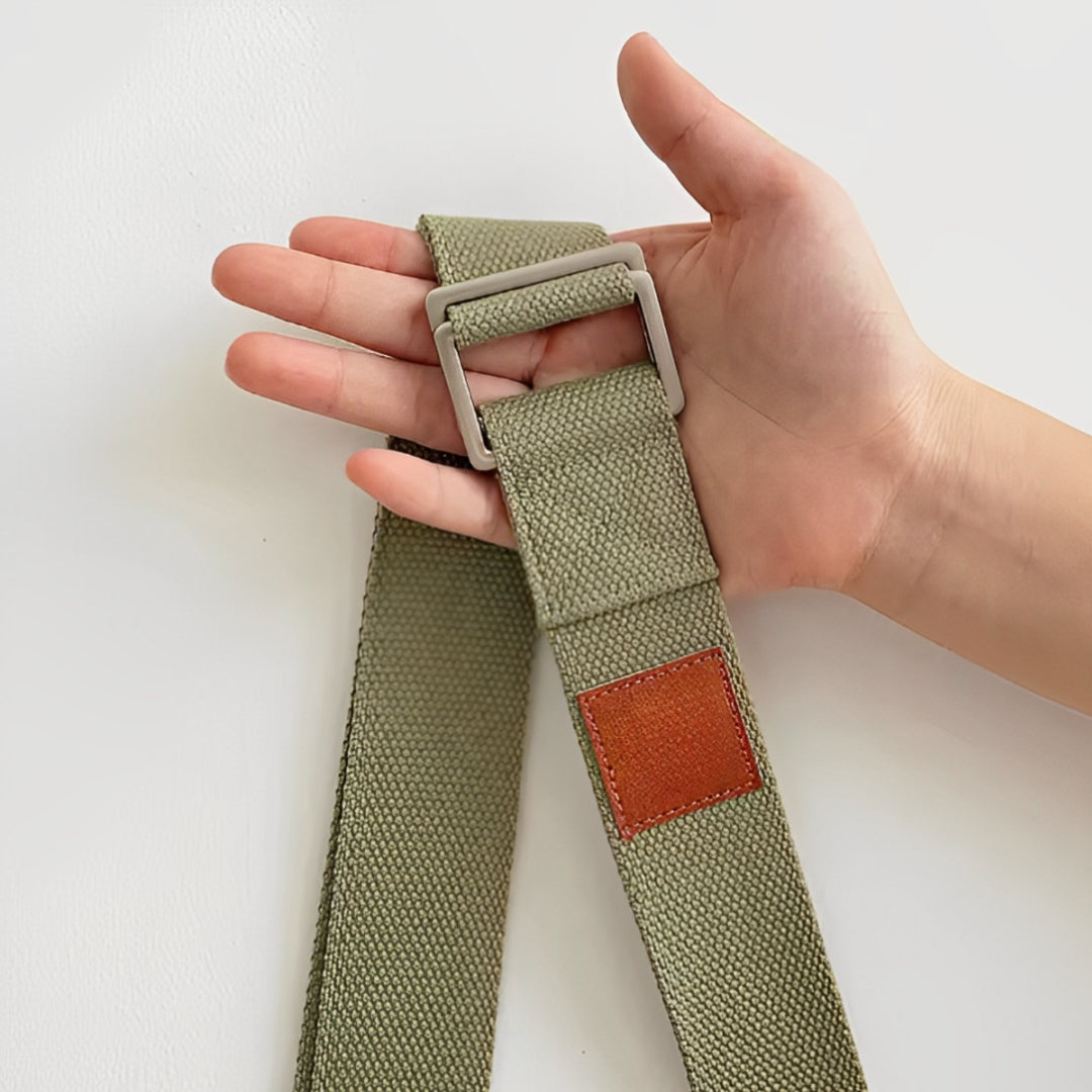 A person holding the FlexCore yoga strap in sage green, featuring a durable metal buckle and a stitched leather accent. Designed for enhancing flexibility, improving posture, and providing support in yoga and stretching exercises. Crafted from high-quality, eco-friendly cotton for a comfortable and secure grip.