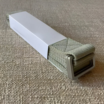 The FlexCore yoga strap in a calming sage green color, featuring a sturdy metal buckle for secure and adjustable support. Made from high-quality, eco-friendly cotton, this durable strap is perfect for deepening stretches, improving flexibility, and enhancing stability in yoga practice.