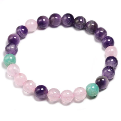 Image of the Mystic Mala, a 108-bead necklace and bracelet made from natural Amethyst, Rose Quartz, and Amazonite stones. It features a vibrant purple tassel and is elegantly displayed on a rustic wooden background, showcasing its spiritual and calming design, ideal for meditation or as a stylish accessory.