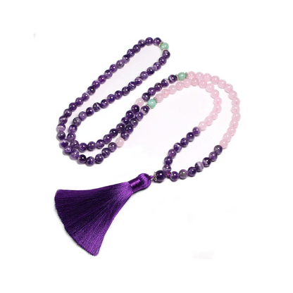 Image of the Mystic Mala, a 108-bead necklace and bracelet made from natural Amethyst, Rose Quartz, and Amazonite stones. It features a vibrant purple tassel and is elegantly displayed on a rustic wooden background, showcasing its spiritual and calming design, ideal for meditation or as a stylish accessory.