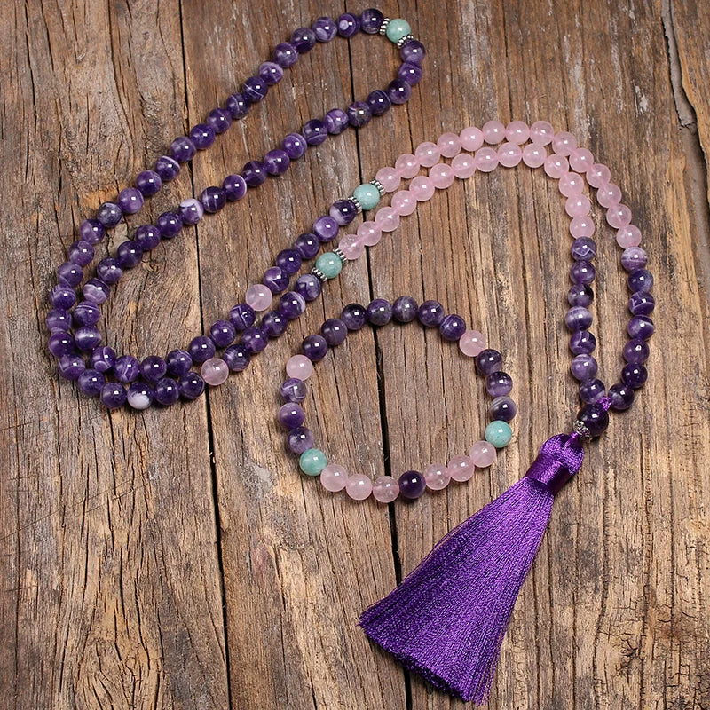 Image of the Mystic Mala, a 108-bead necklace and bracelet made from natural Amethyst, Rose Quartz, and Amazonite stones. It features a vibrant purple tassel and is elegantly displayed on a rustic wooden background, showcasing its spiritual and calming design, ideal for meditation or as a stylish accessory.