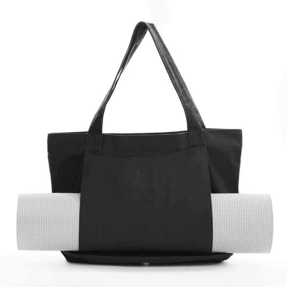 Image of the Essence Yoga Tote, a black, washable canvas bag designed for carrying yoga mats and workout essentials. The tote features a sleek and spacious design with adjustable straps for easy carrying. Shown with a rolled yoga mat secured in its front pocket, the tote is lightweight, foldable, and perfect for yogis on the go.